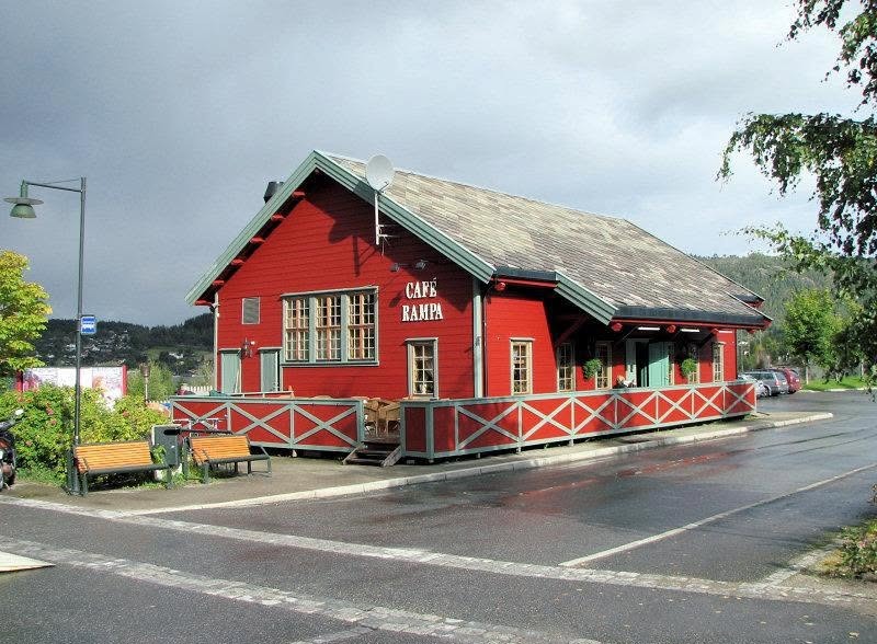 Cafè Rampa sett fra gata en regnvåt dag, med benker og lyktestolpe utenfor