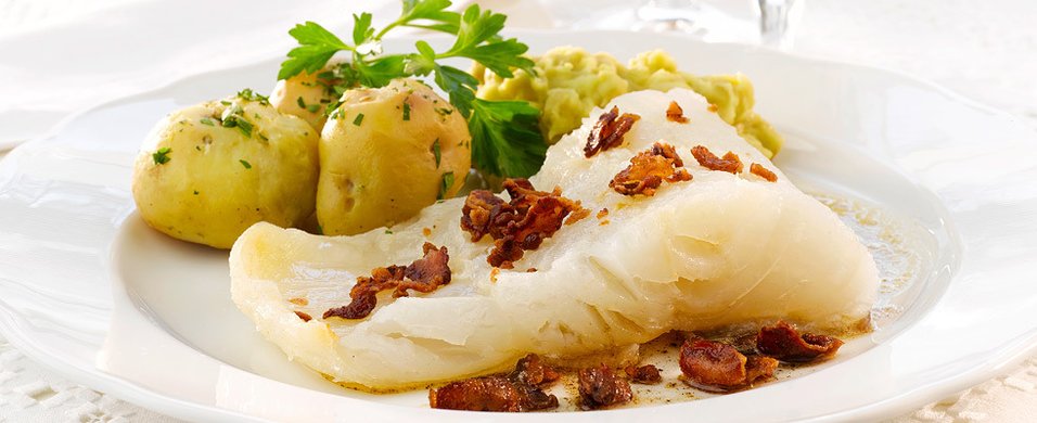 Lutefisk servert med mandelpoteter, ertestuing og sprøstekt bacon